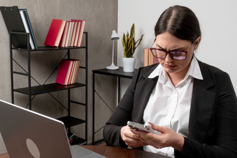 Frau in einem Büro tippt auf einem Smartphone